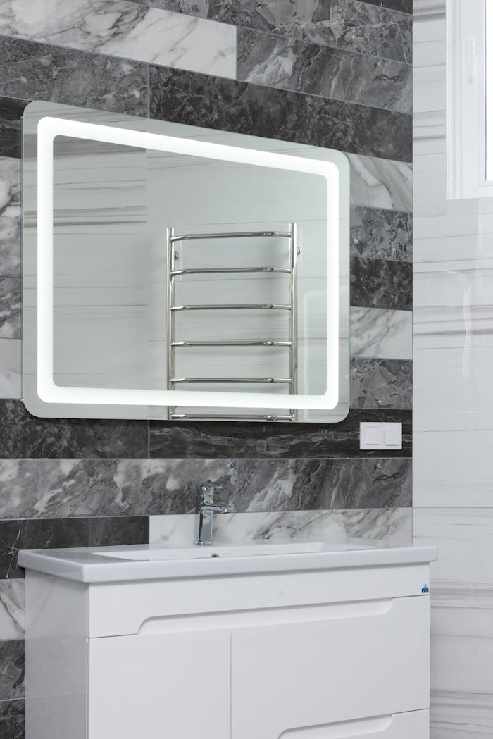 Contemporary bathroom with stainless steel tap and washstand under mirror reflecting metal rack in house